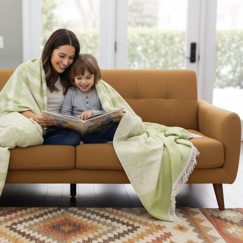 sofa with a  reversible green and ecru wearable throw draped over it in a living room setting.