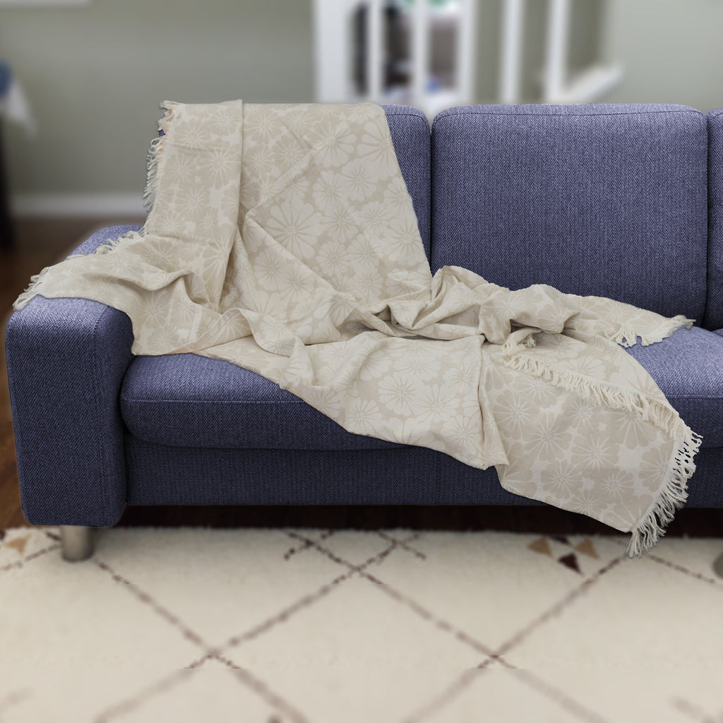 reversible wearable throw in pure cotton of bloom design in beige color, from Hem And Tassel, draped on a blue sofa