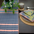 textured slub-cotton table runner of rough stripes design with blue color accent on dining table with place setting and plant - from Hem And Tassel