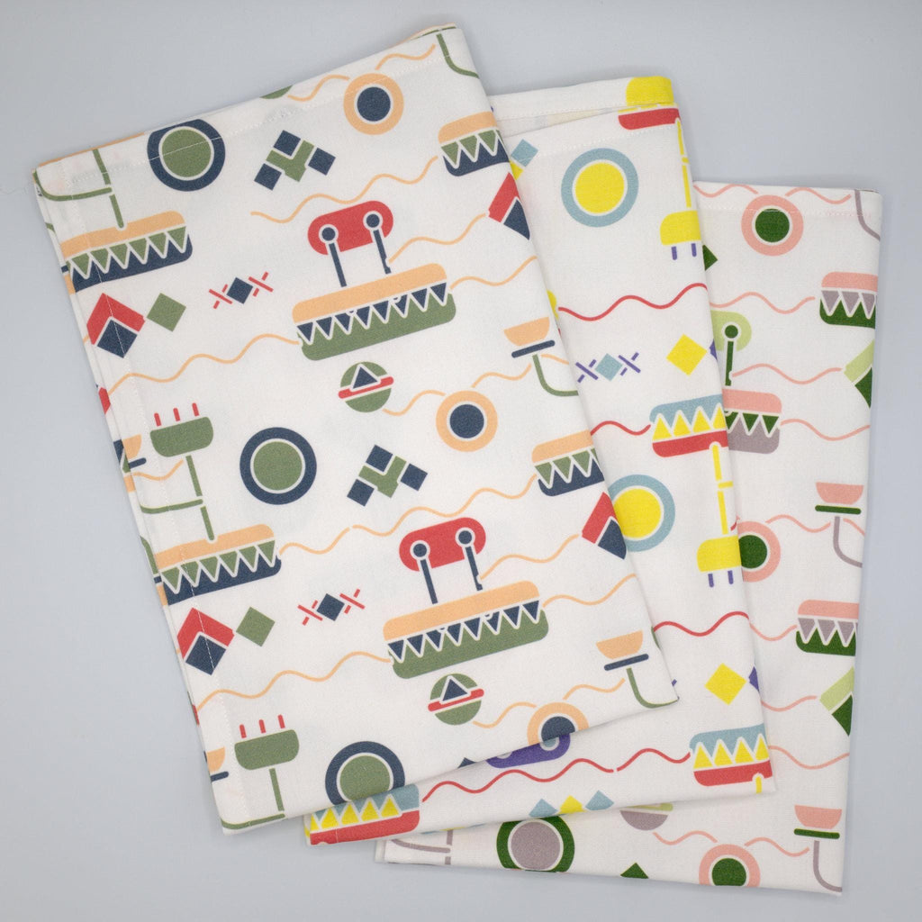 set of three colorful cotton percale tea towels of thingies design fanned on grey background
