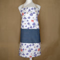 Colorful floral shy dragonfly apron on a mannequin against a brown background from Hem And Tassel 