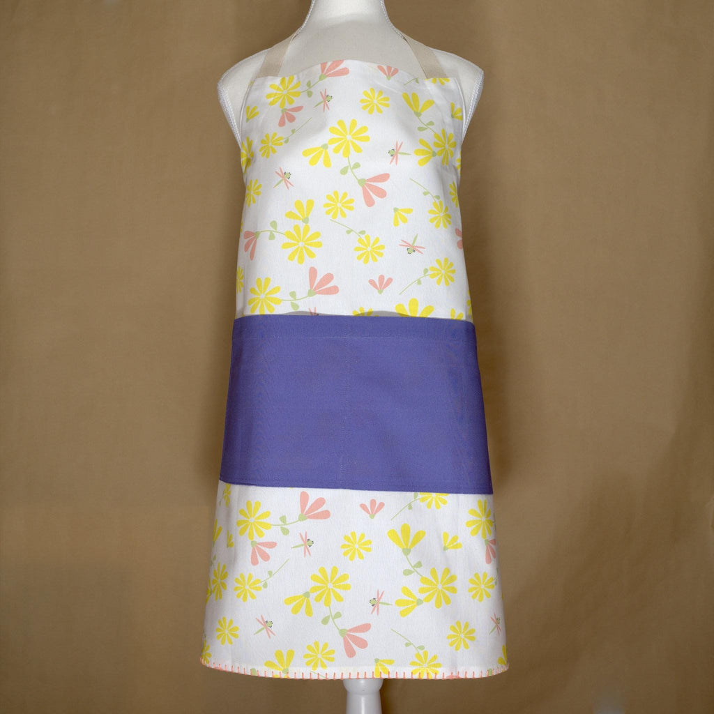 Colorful shy dragonfly apron with yellow and pink floral pattern on a mannequin against a brown background from Hem And Tassel 