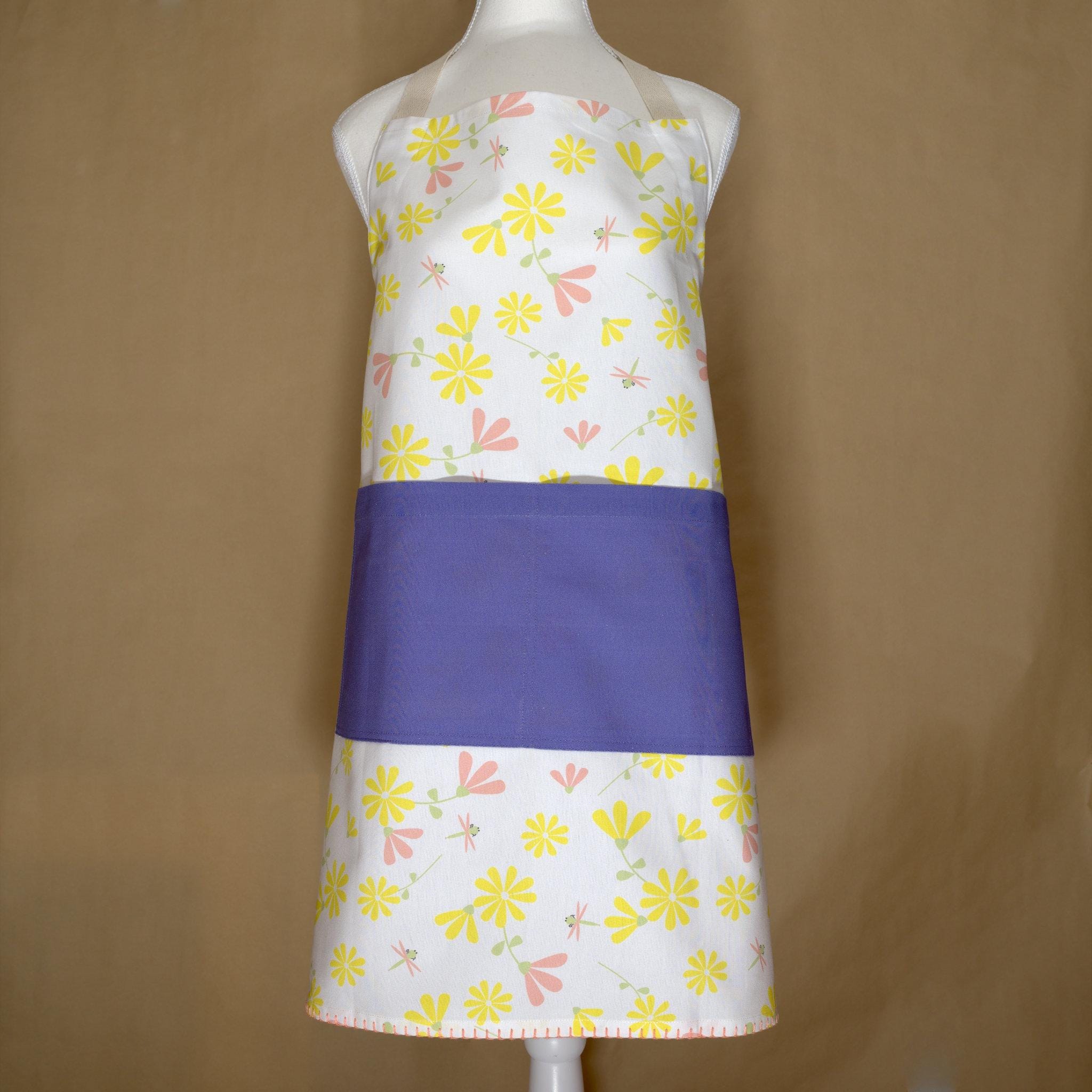 Colorful shy dragonfly apron with yellow and pink floral pattern on a mannequin against a brown background from Hem And Tassel 