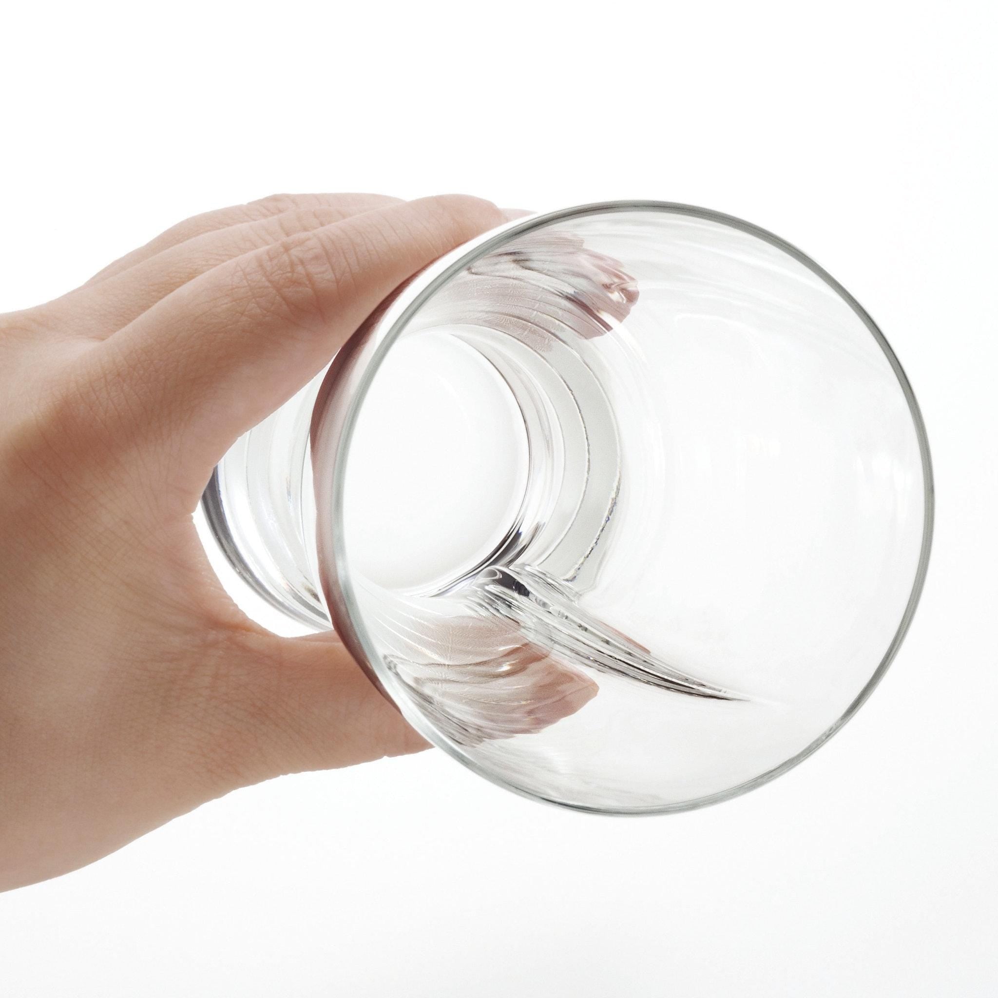 empty slash beer glass made in Japan, seen from top held by a human hand from Hem And Tassel on a white background