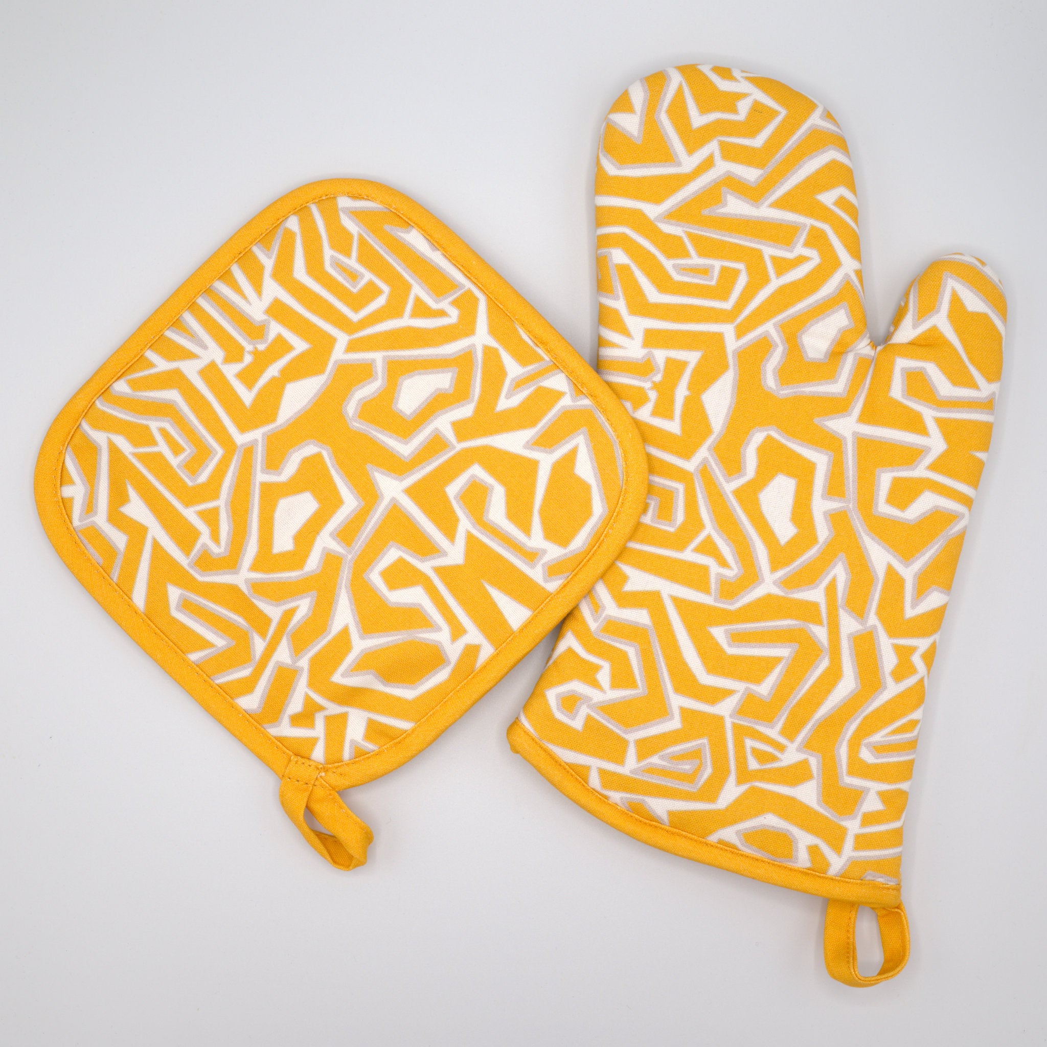 squggles orange and white patterned pot holder and oven mitt on a light gray background from Hem And Tassel 