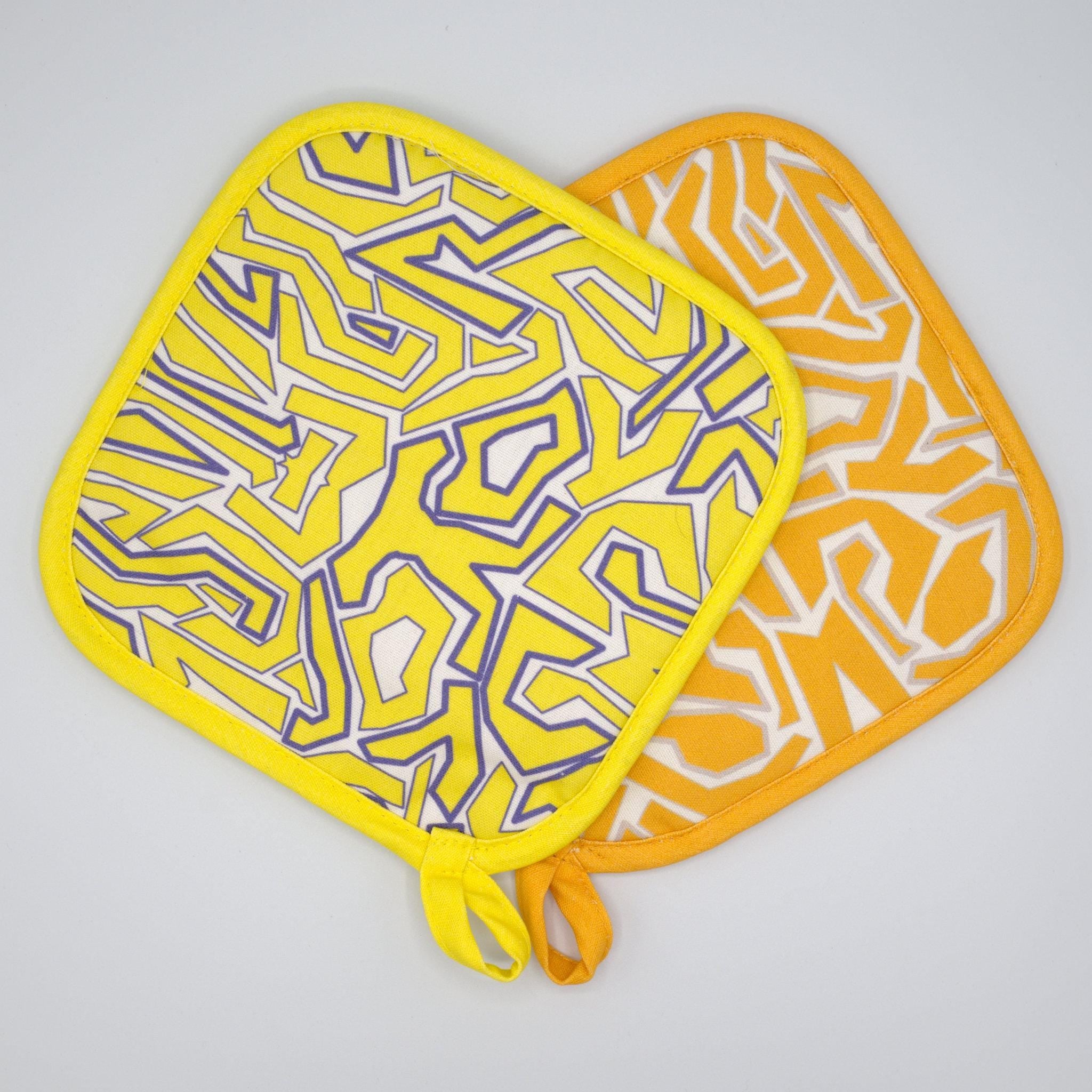 Two squggles  pot holders with geometric patterns on a gray background from Hem And Tassel 