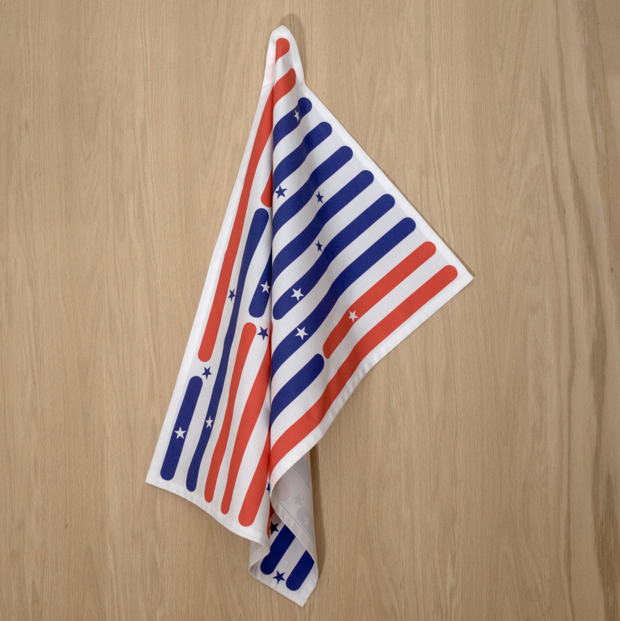 Towel with American flag design on a wooden surface from Hem And Tassel 