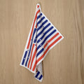 Towel with American flag design on a wooden surface from Hem And Tassel 