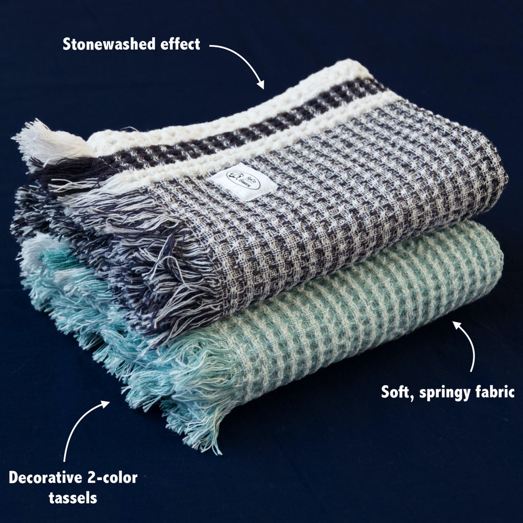 Stack of stonewashed waffle towels with text highlighting stonewashed effect, soft fabric, and decorative tassels on a dark background from Hem And Tassel 