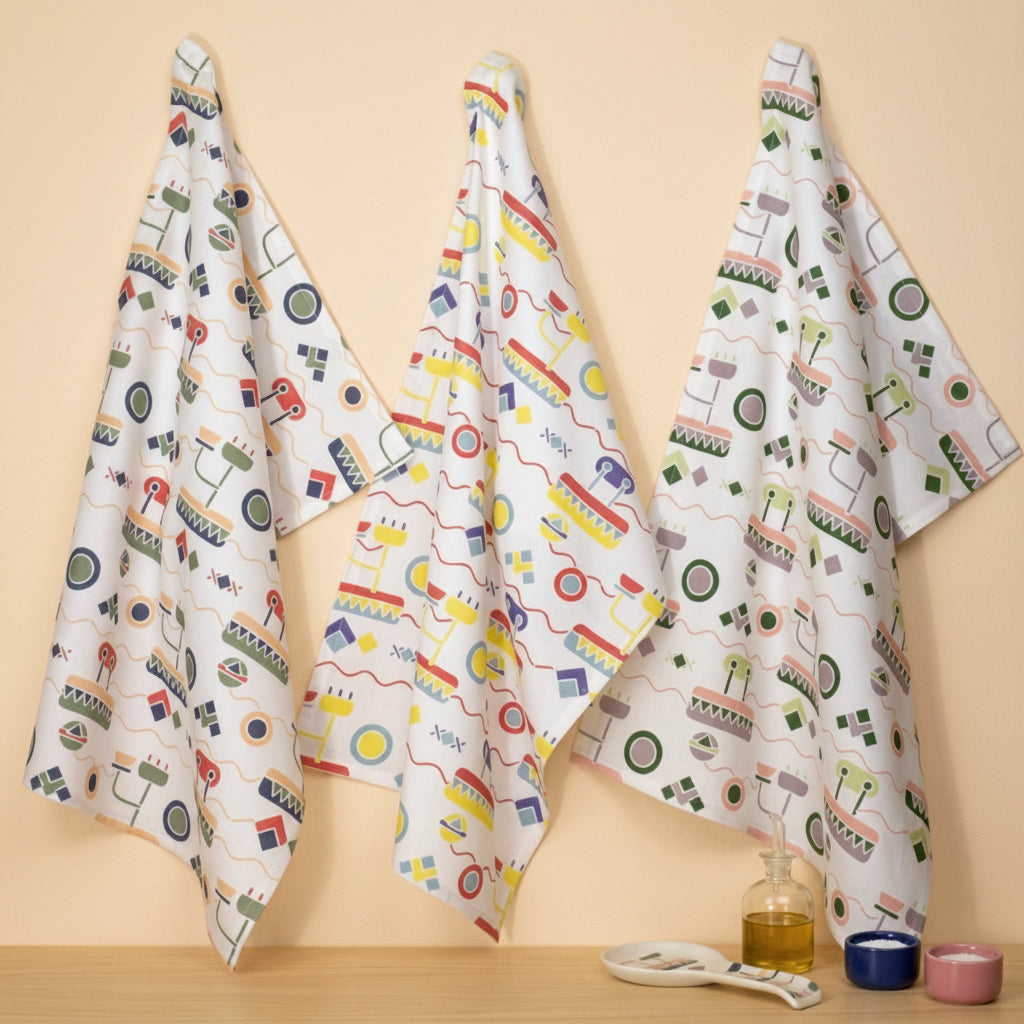 three cotton kitchen towels hanging on a light beige wall with salt and oil on a kitchen counter below