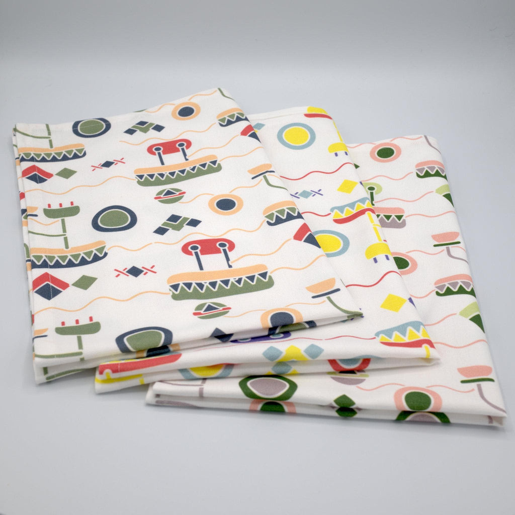 set of three colorful cotton percale tea towels of thingies design folded on grey background