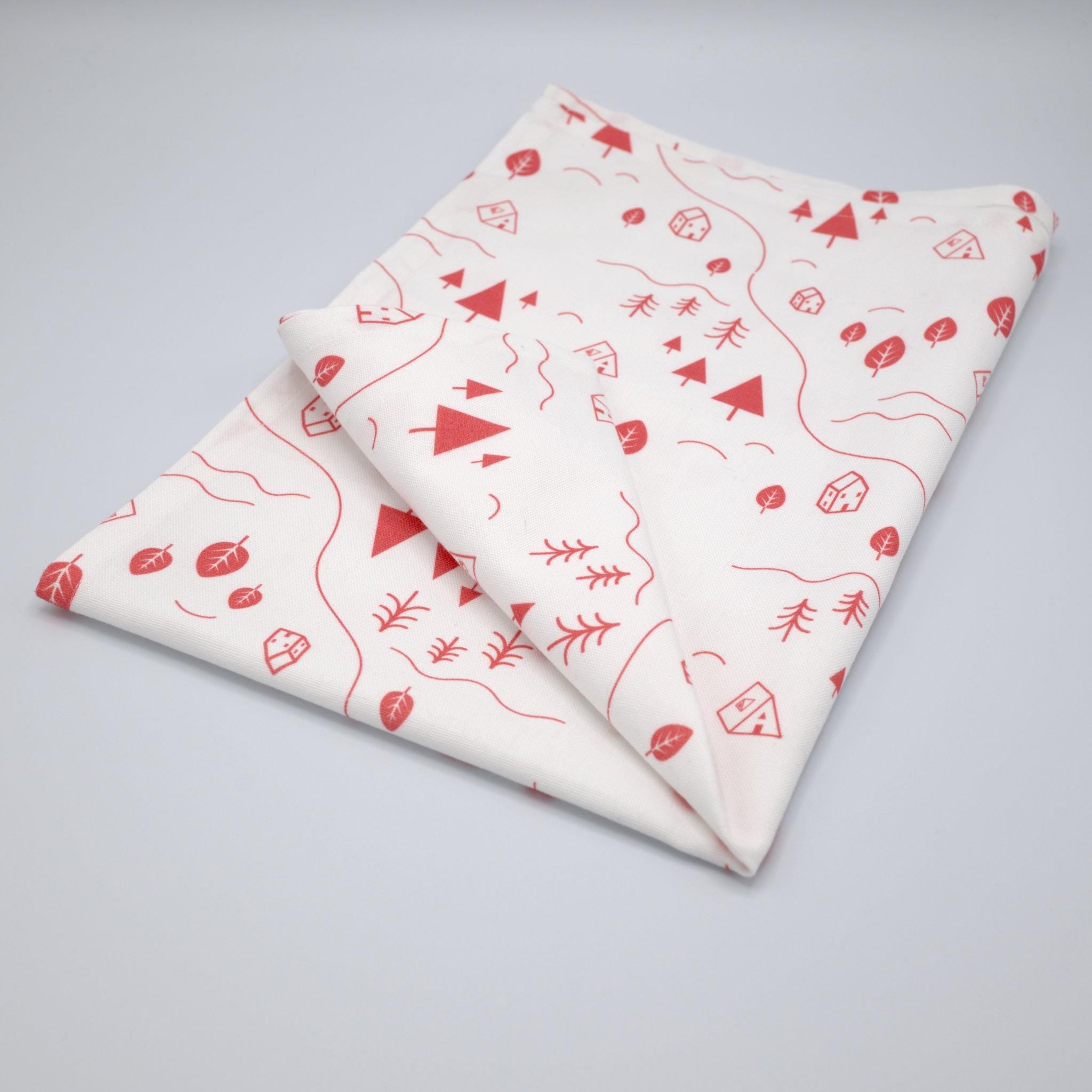 tiny countryside kitchen towel folded with pink patterns on a gray background from Hem And Tassel 