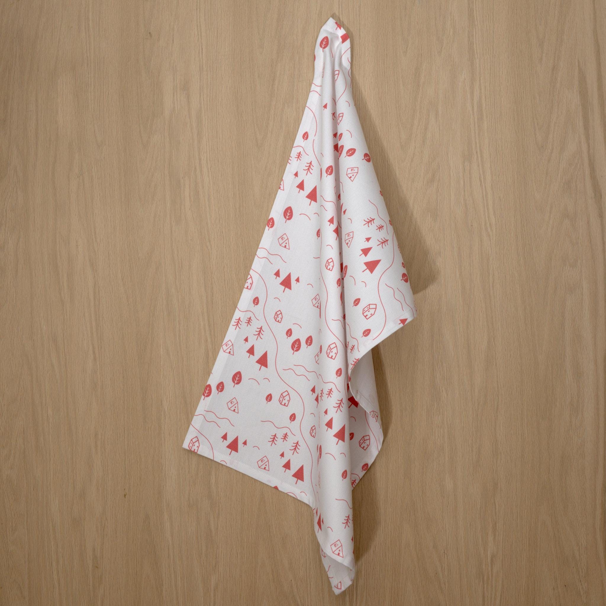 rich cotton percale kitchen towel of tiny countryside design in pink color against a wooden background- from Hem And Tassel