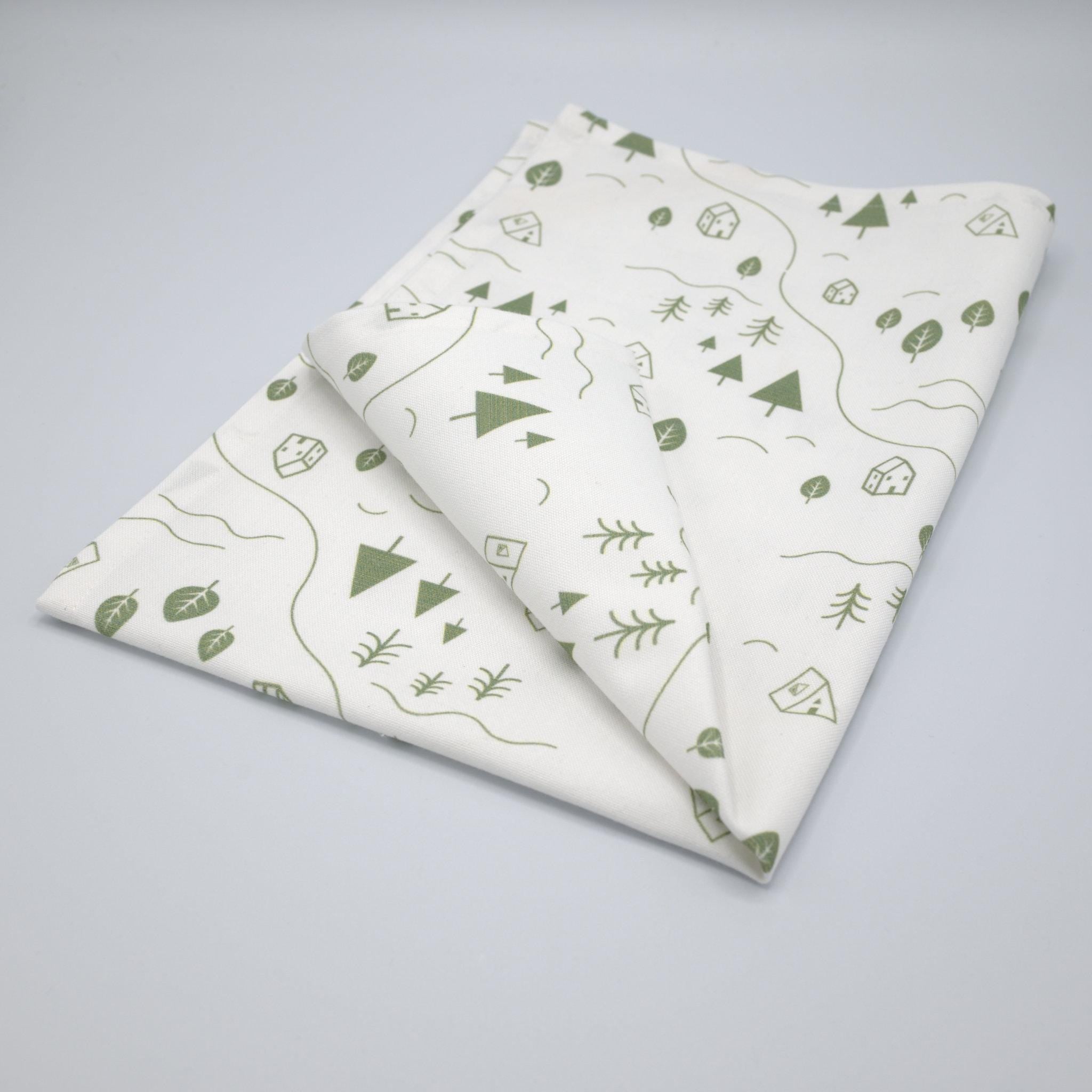 tiny countryside towel with green nature-themed patterns on a gray background from Hem And Tassel 