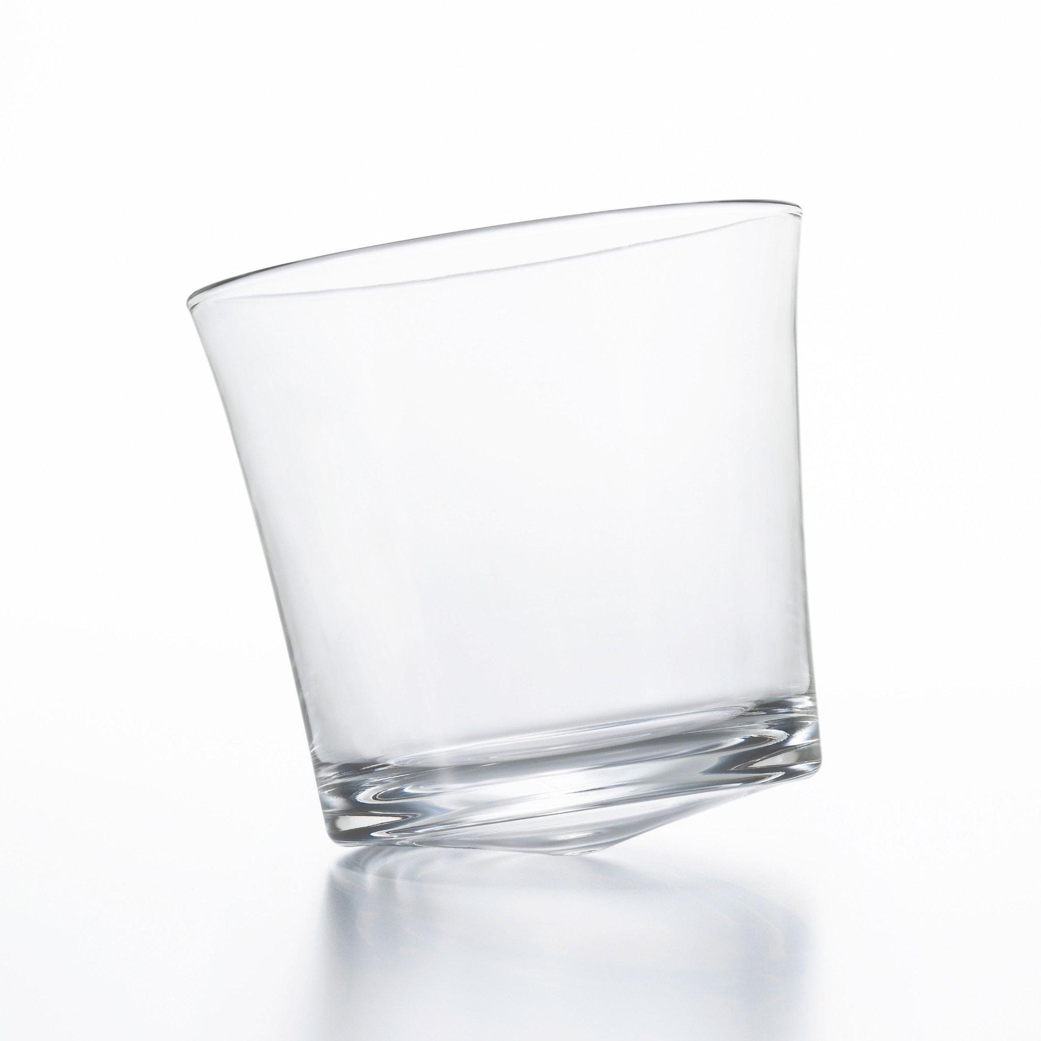 designer tottering whiskey glass made in Japan from Hem And Tassel, sitting empty and inclined on a white background