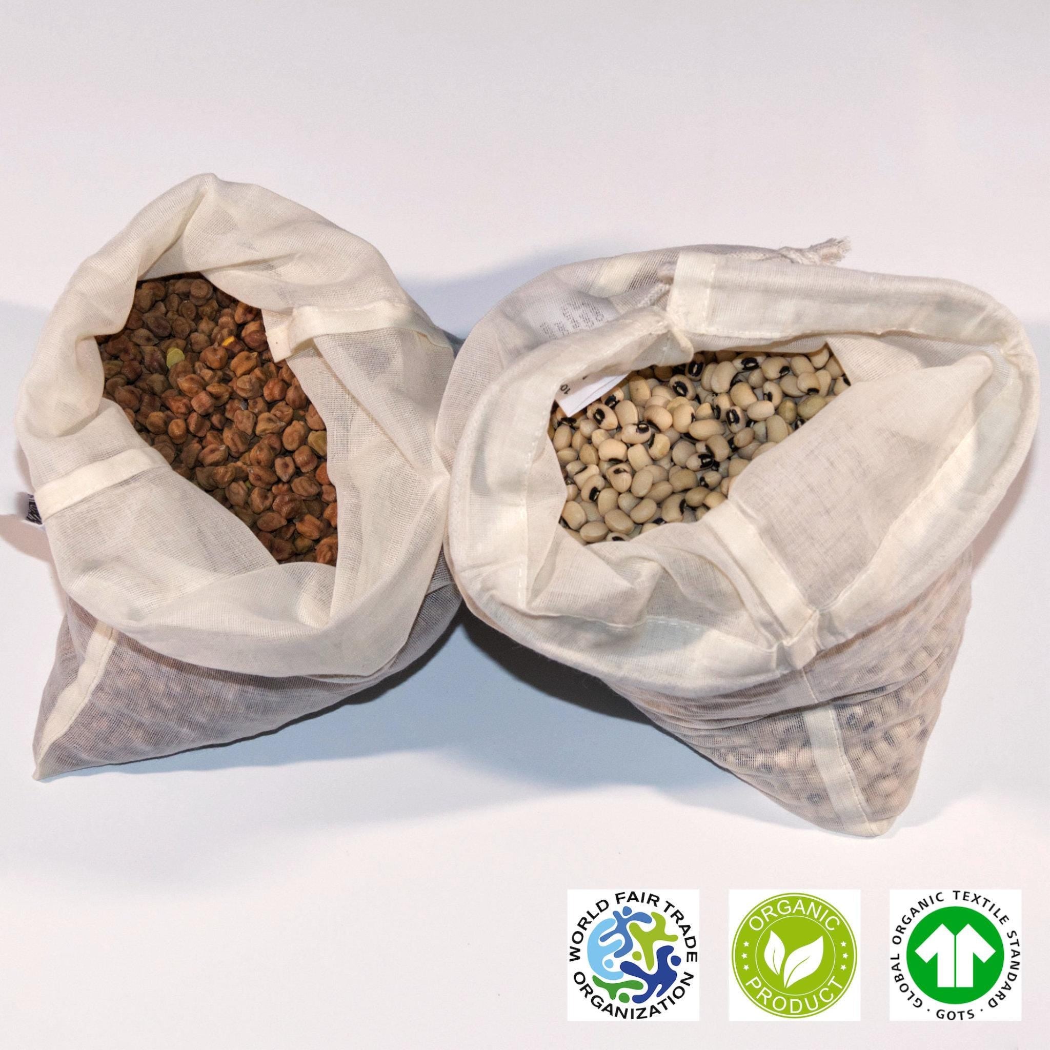 Two open organic cotton produce bags filled with seeds on a white background, featuring Fair Trade and Organic certification logos