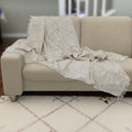 reversible wearable throw in pure cotton of bloom design in beige color, from Hem And Tassel, draped on a sofa