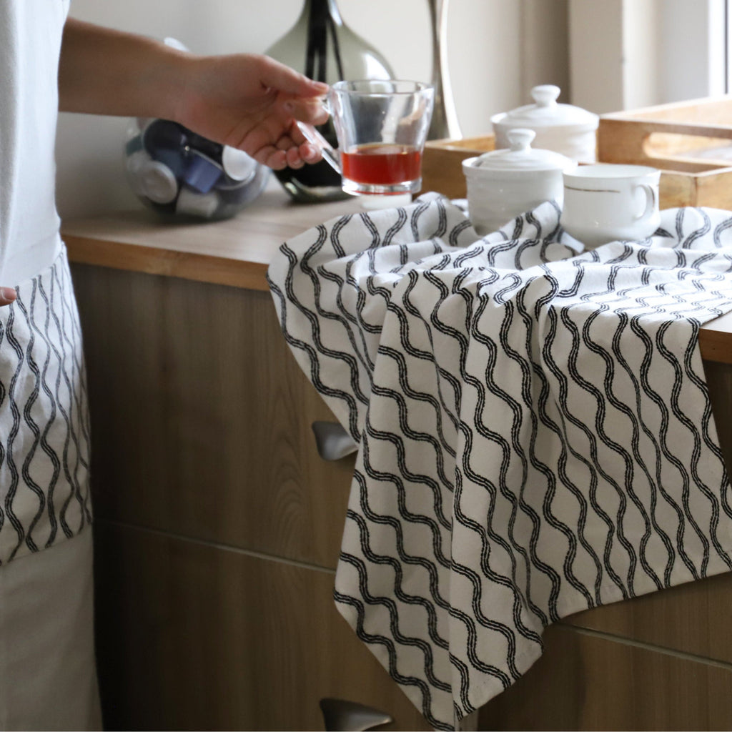 white flour sack towel in steams pattern with in kitchen with person holding tea cup from Hem And Tassel 