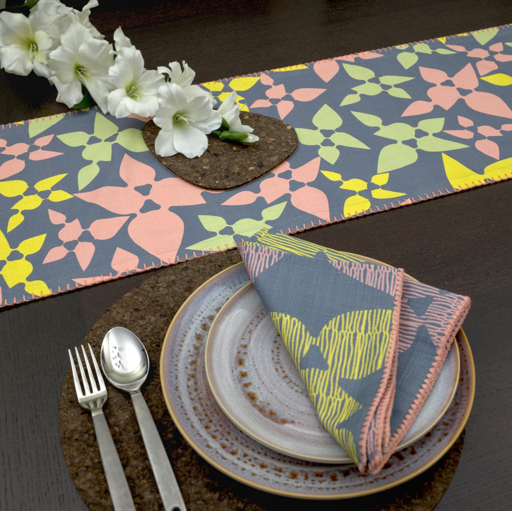 celebration slub cotton table runner with colors on dark grey, on wooden dining table with matching dinner napkins and place setting - from Hem And Tassel