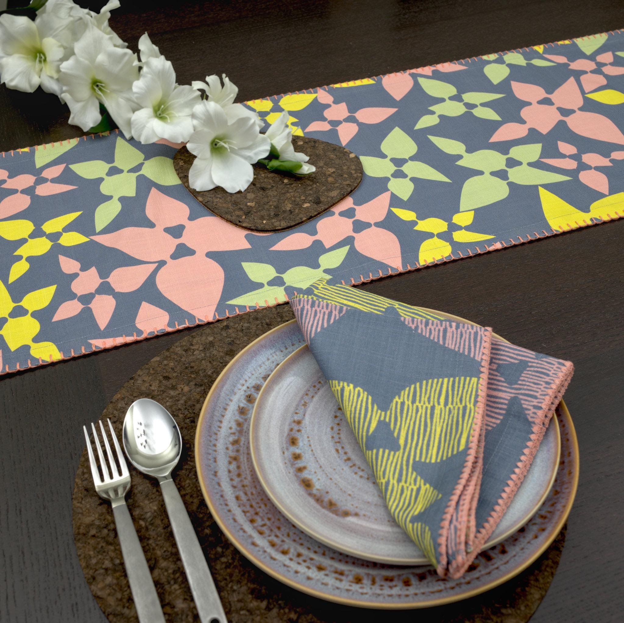 celebration slub cotton table runner with colors on dark grey, on wooden dining table with matching dinner napkins and place setting - from Hem And Tassel