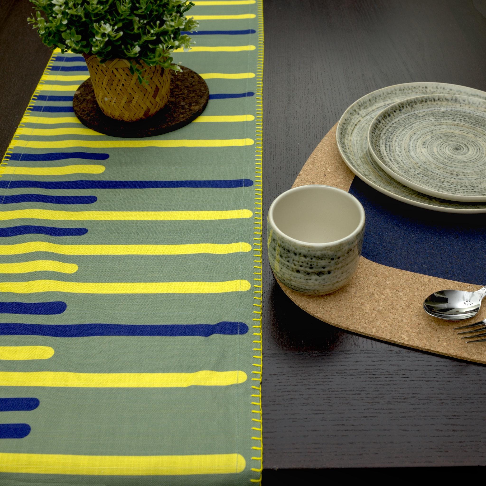 textured slub cotton table runner of yellow piano design with decorative hems and place setting on kidney bean cork placemat - from Hem And Tassel