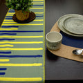 textured slub cotton table runner of yellow piano design with decorative hems and place setting on kidney bean cork placemat - from Hem And Tassel