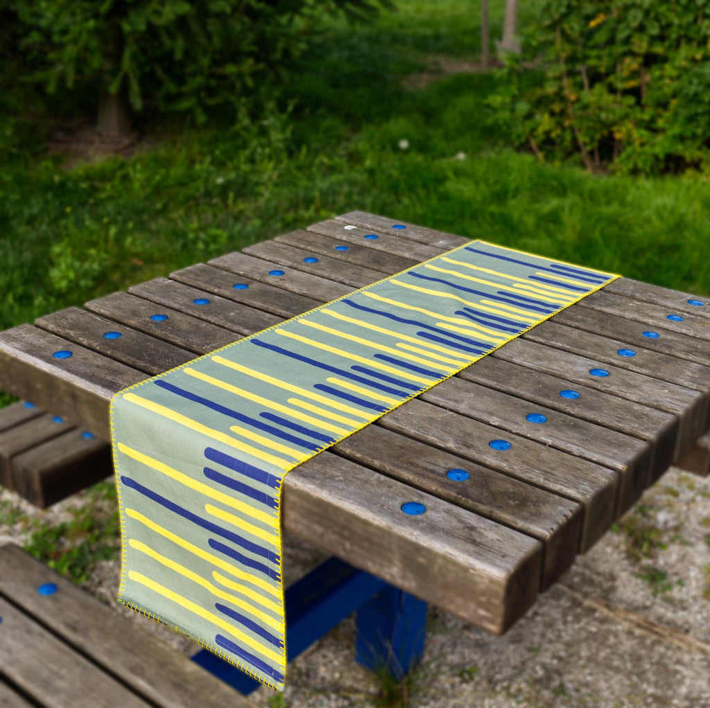 yellow piano table runner with blue and yellow pattern on a wooden table outdoors from Hem And Tassel 