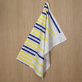 rich percale cotton tea towel of horizontal yellow piano design hanging against a wooden background- from Hem And Tassel