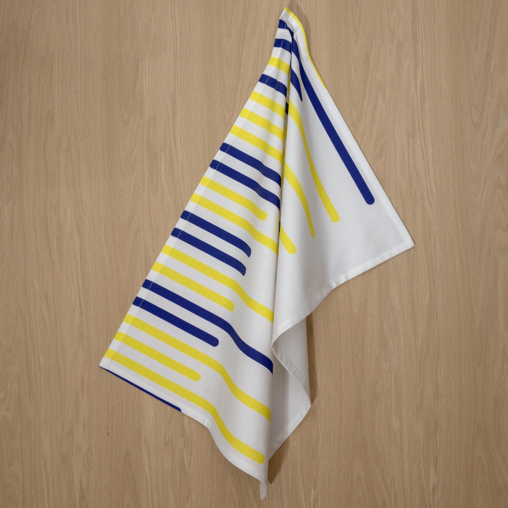 Striped yellow piano tea towel with horizontal blue and yellow lines on a wooden surface from Hem And Tassel 
