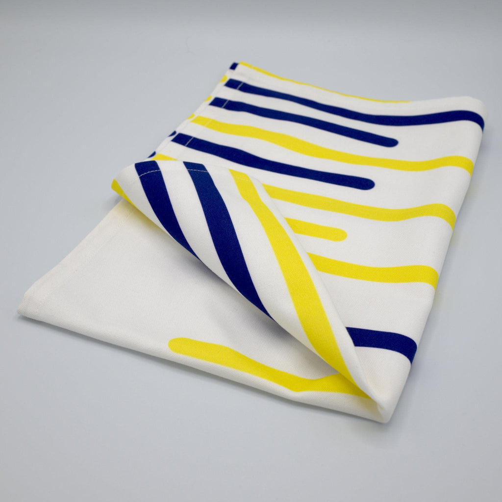 Folded yellow piano tea towel with blue and yellow stripes on a gray background from Hem And Tassel 