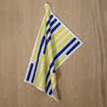 Striped yellow piano tea towel with vertical blue and yellow lines on a wooden surface from Hem And Tassel 