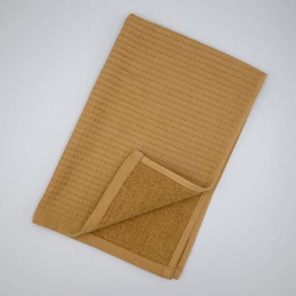 Jekyll and Hyde design tea towel in camel flat folded from hem and tassel