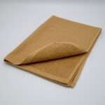 Jekyll and Hyde design tea towel in camel folded from hem and tassel