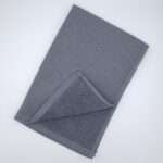 Jekyll and Hyde design tea towel in grey flat folded from hem and tassel