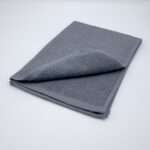 Jekyll and Hyde design tea towel in grey folded from hem and tassel