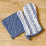 Quilted Decade classic oven mitt and pot holder shown in blue color on a wooden table
