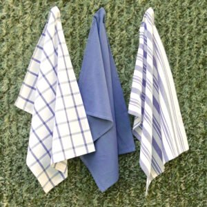 Three large 100% cotton kitchen towels in flat weave shown hanging, of decade classic style, in solid blue, checks and stripes