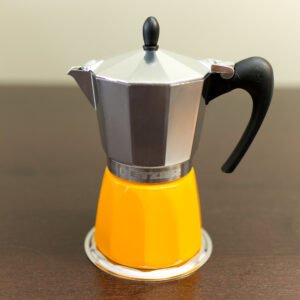 Induction Moka Pot with a yellow boiler and lid shut, sitting on a table top