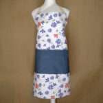 Shy dragonfly design apron with purple flowers on mannequin from hem and tassel