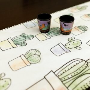 Table runner with hazy desert cactus print close up and 2 shot glasses