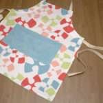 flock and flutter design apron in slate flat from hem and tassel