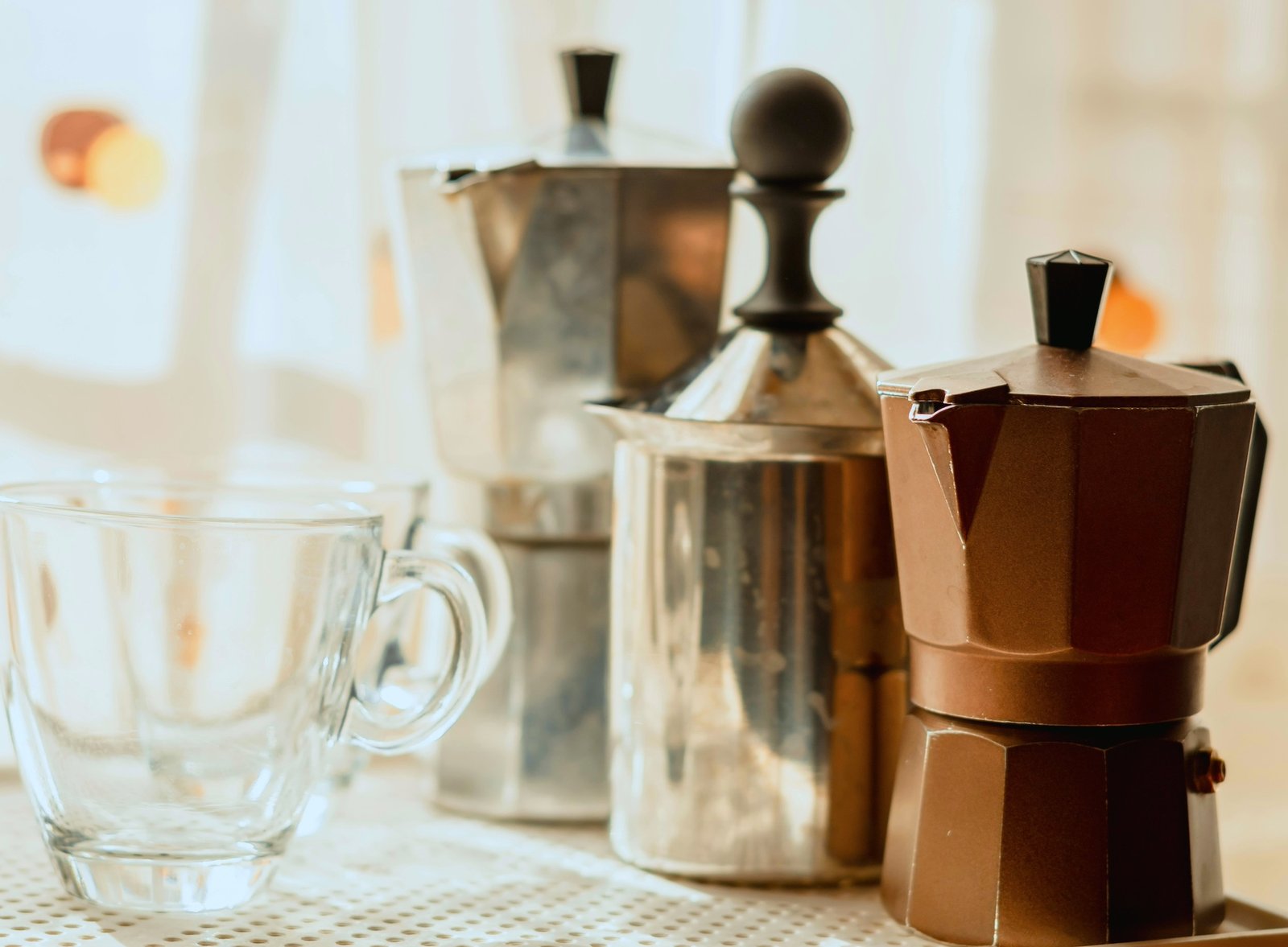 kitchen setting showing two moka pots, cup and milk frother