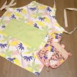 pollen up design apron in mint flat with blush oven mitt and pot holderfrom hem and tassel
