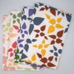 Celebration design four tea towels fanned and stacked from hem and tassel