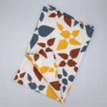 Celebration design tea towel in clay flat folded from hem and tassel