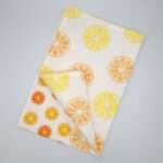 Faded orange design tea towel flat folded from hem and tassel