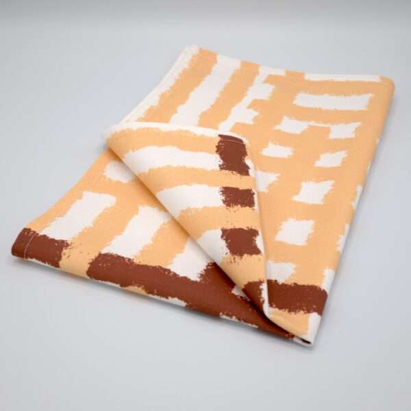 Jute impossible checked design tea towel folded in buff from hem and tassel