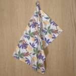 Pollen Up design hanging tea towel in purple from hem and tassel