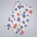 Shy dragonfly hiding design tea towel in purple and pink flat folded from hem and tassel