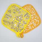Squiggles maze design hot pads in orange and yellow from hem and tassel